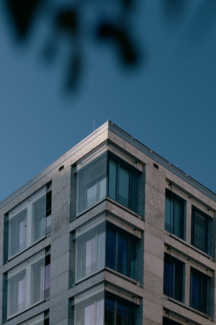 A modern angular building with glass windows in urban setting against a blue sky.